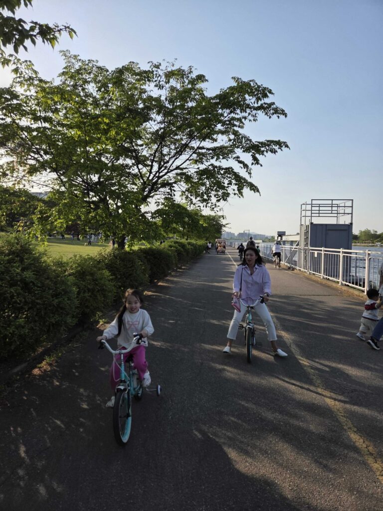 Misari Park Hanam paved river path with a child cycling alongside an adult cyclist