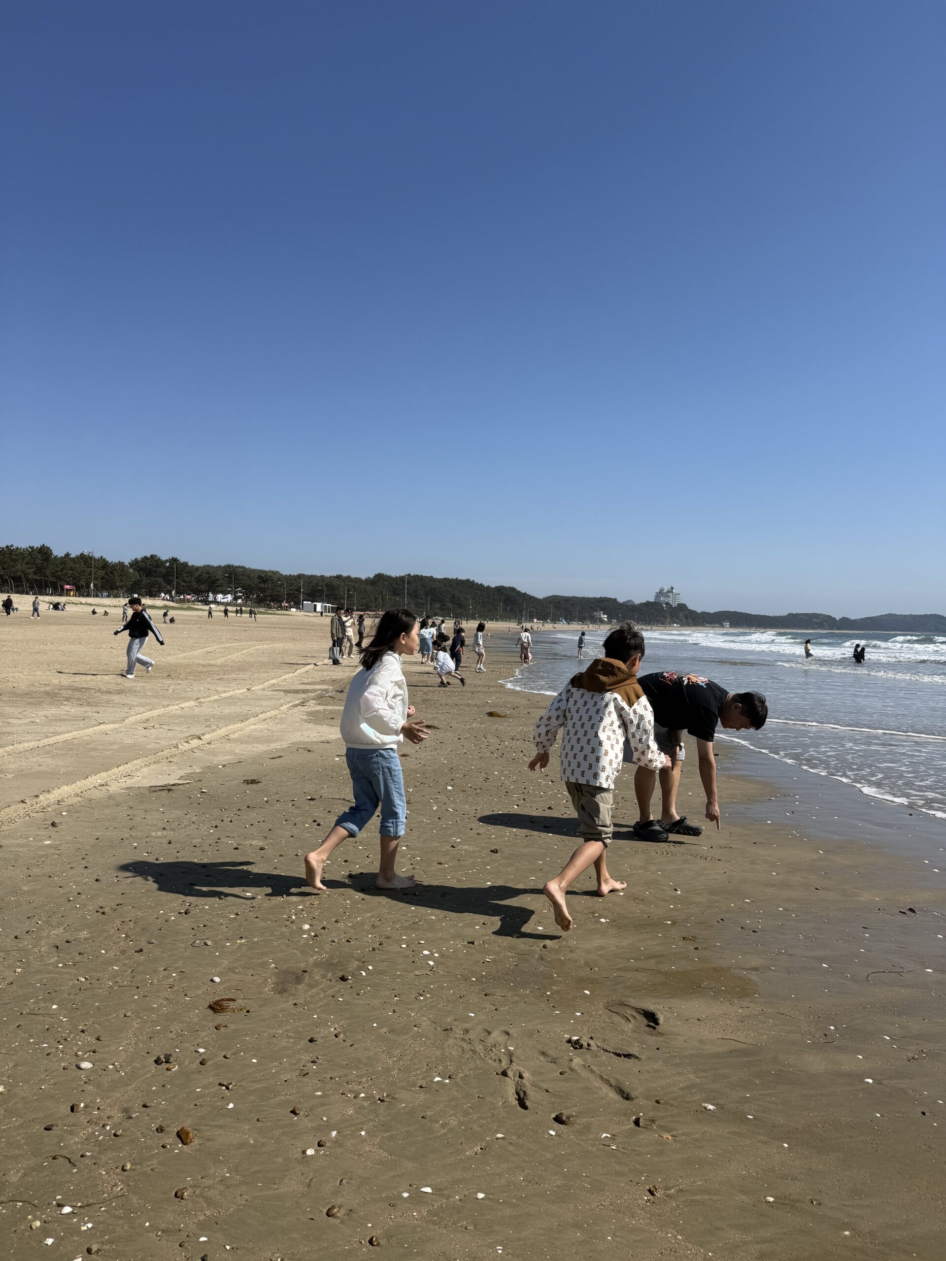 Two kids jumping in air on Kkotji Beach with kids during late afternoon