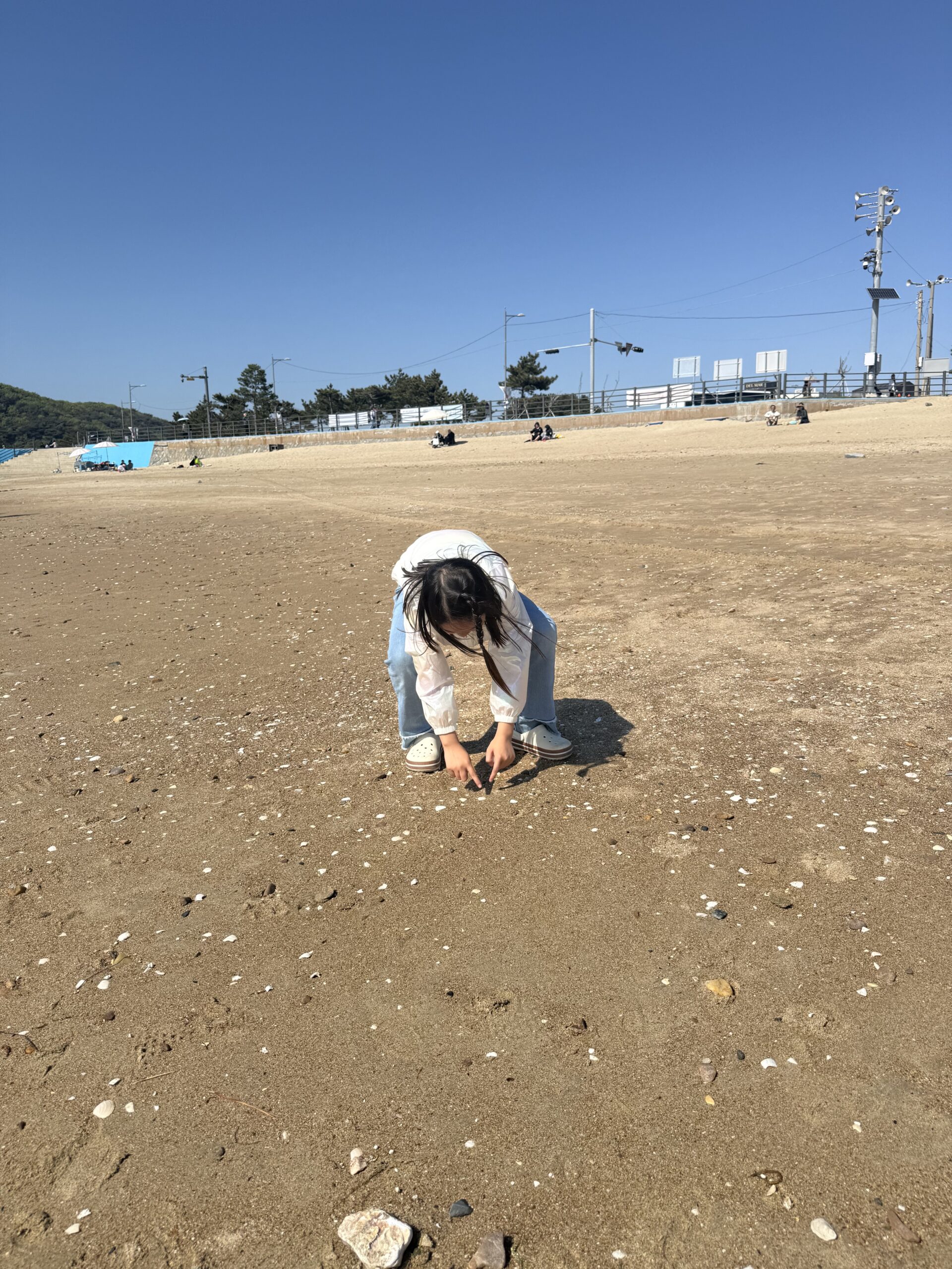 Family of four jumping on Kkotji Beach with kids during family camping trip