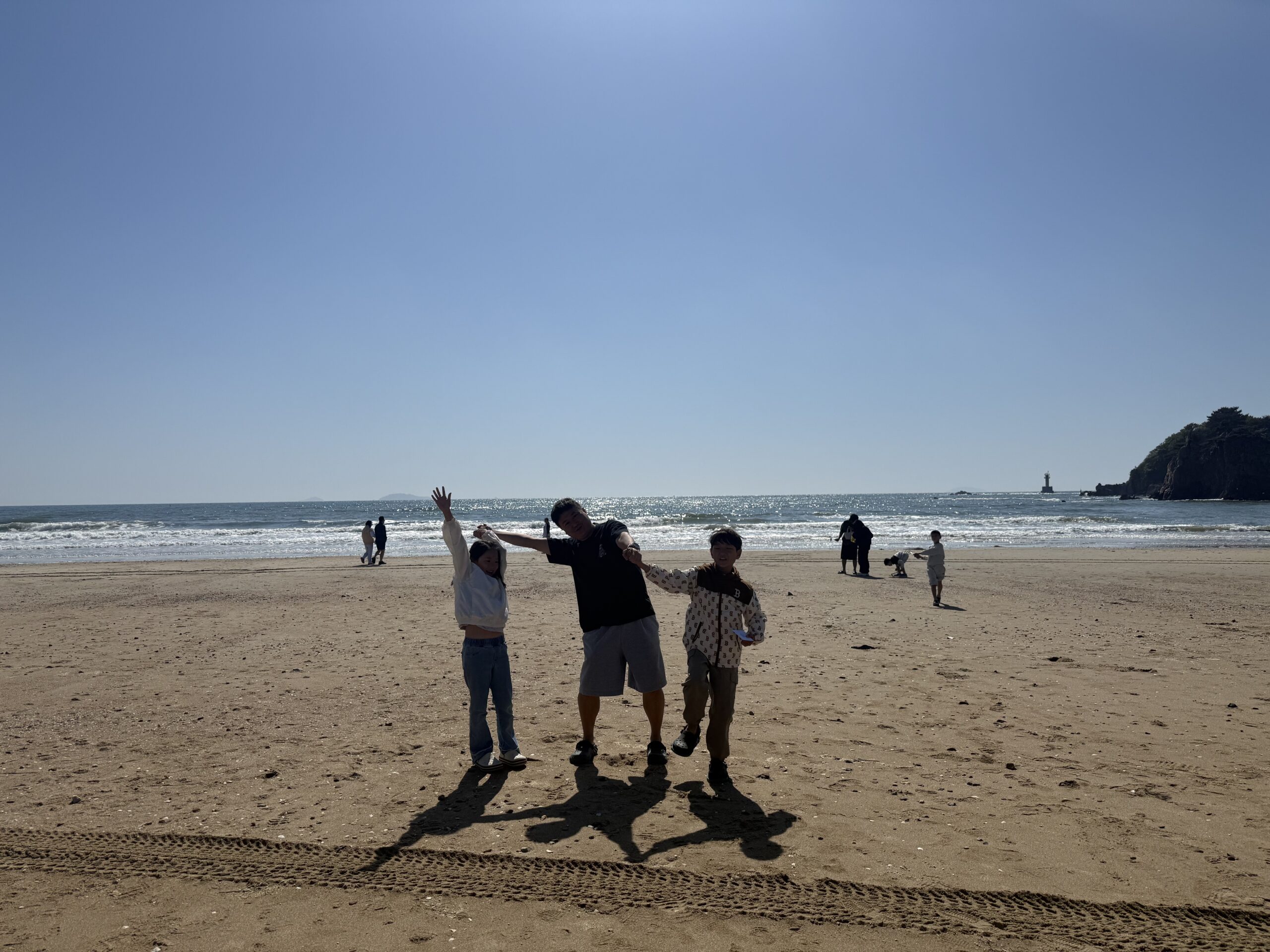 Family silhouette walking on Kkotji Beach in afternoon light
