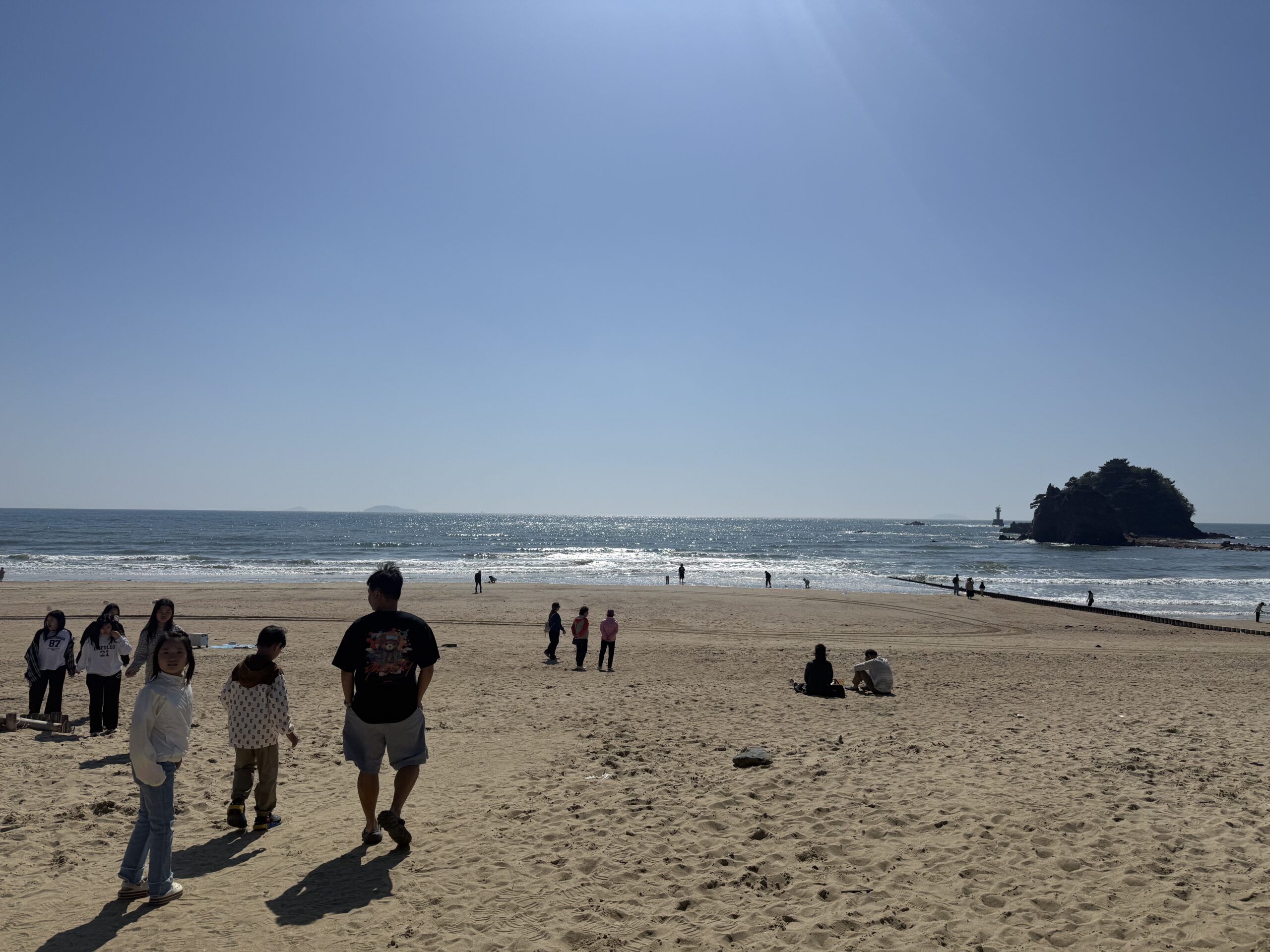 Wide view of Kkotji Beach Anmyeondo with families and small offshore island