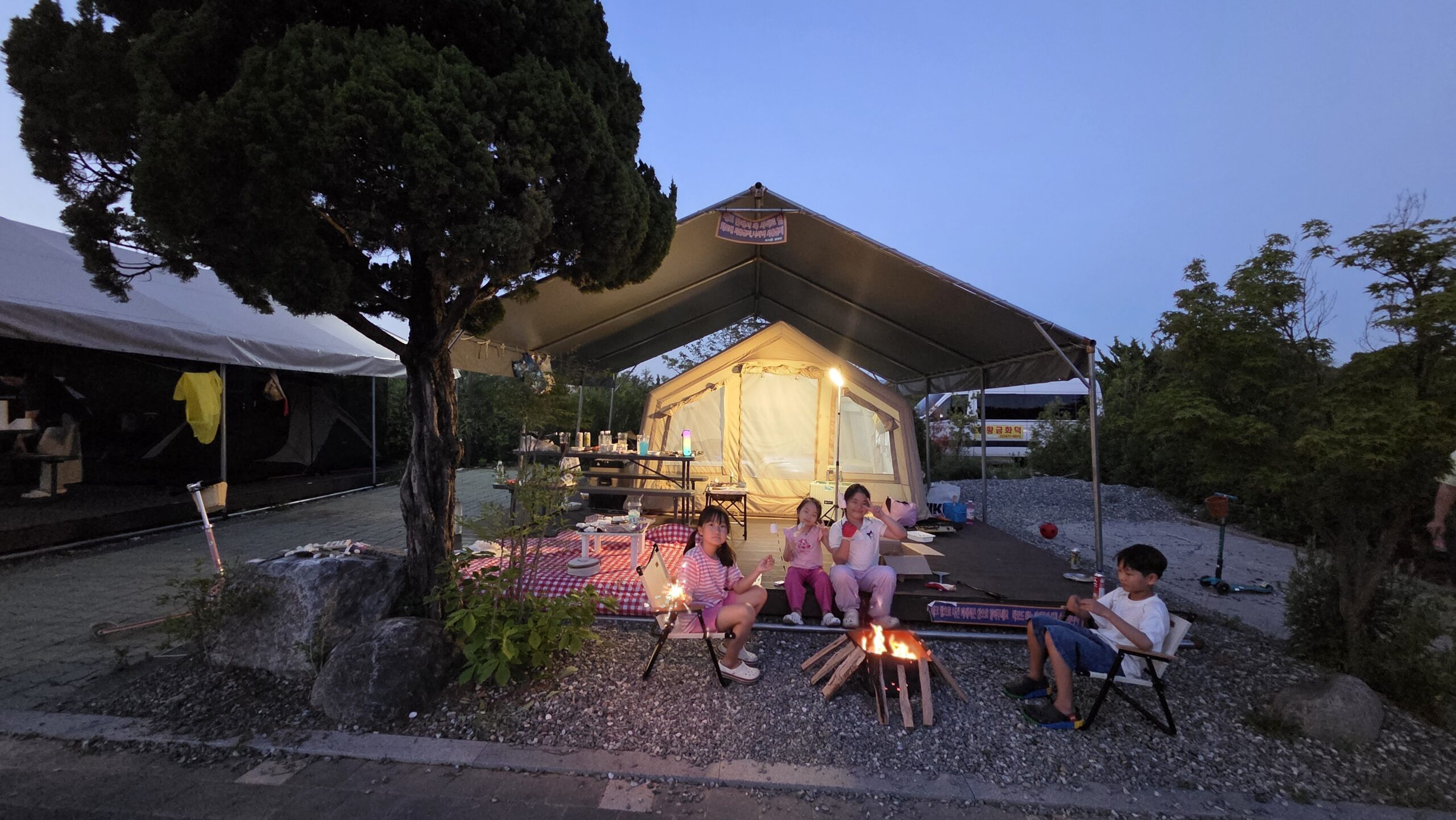 Choihu Camping Hanam glamping site at dusk with four kids by the bonfire