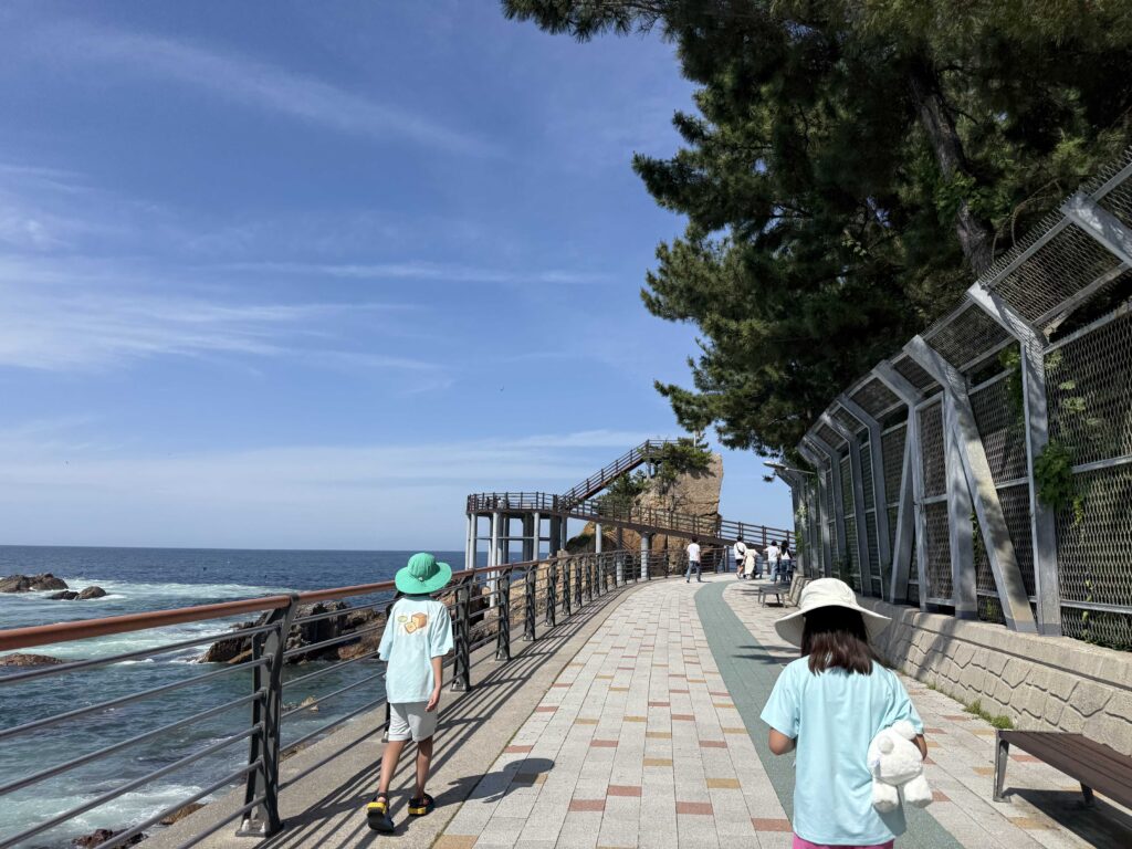 Kids walking toward a sea-stack viewing deck on the Chogok Candlestick Rock Trail in Samcheok
