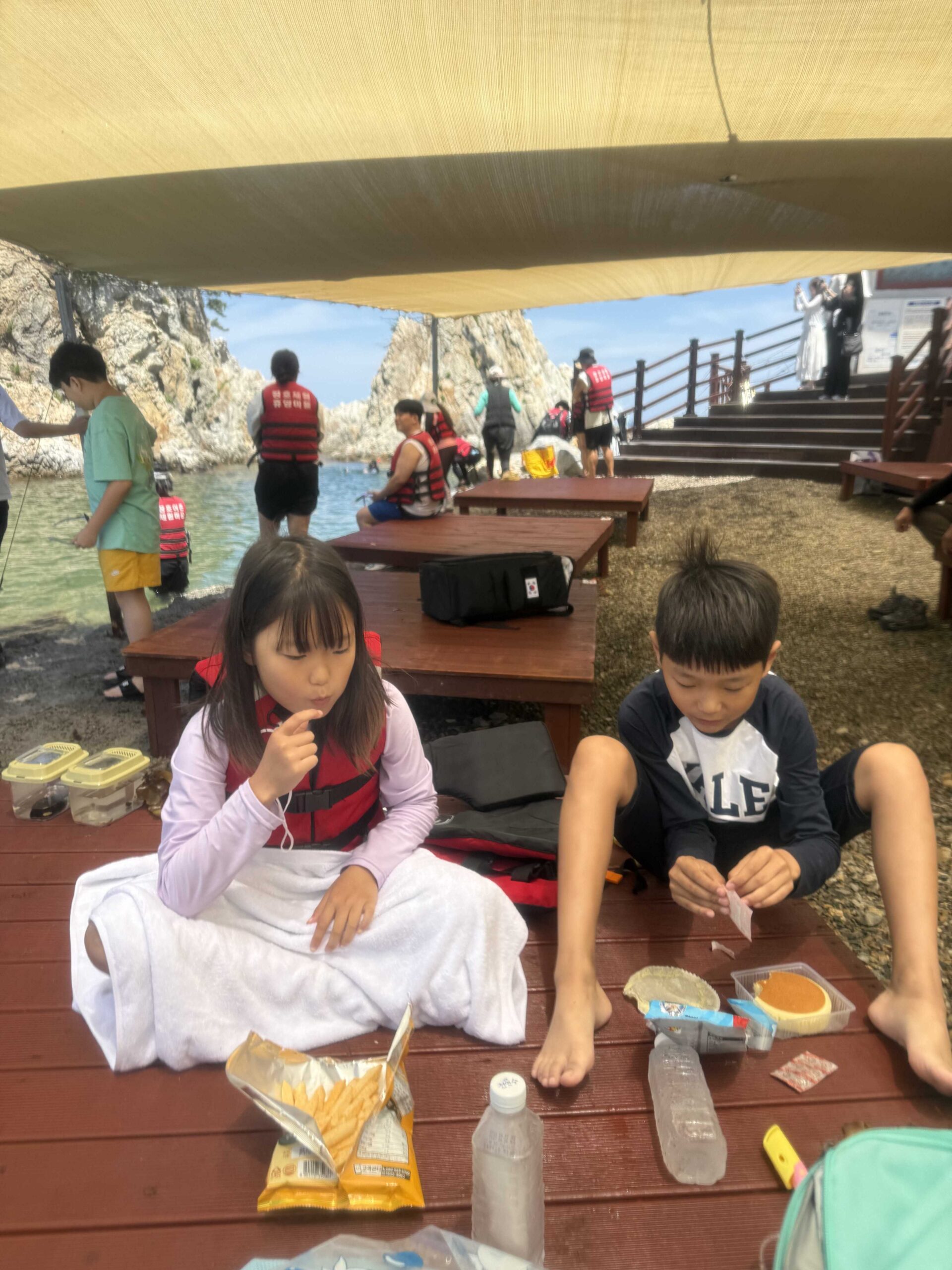 Kids eating snacks under shade on a rented platform at Jangho Beach with kids