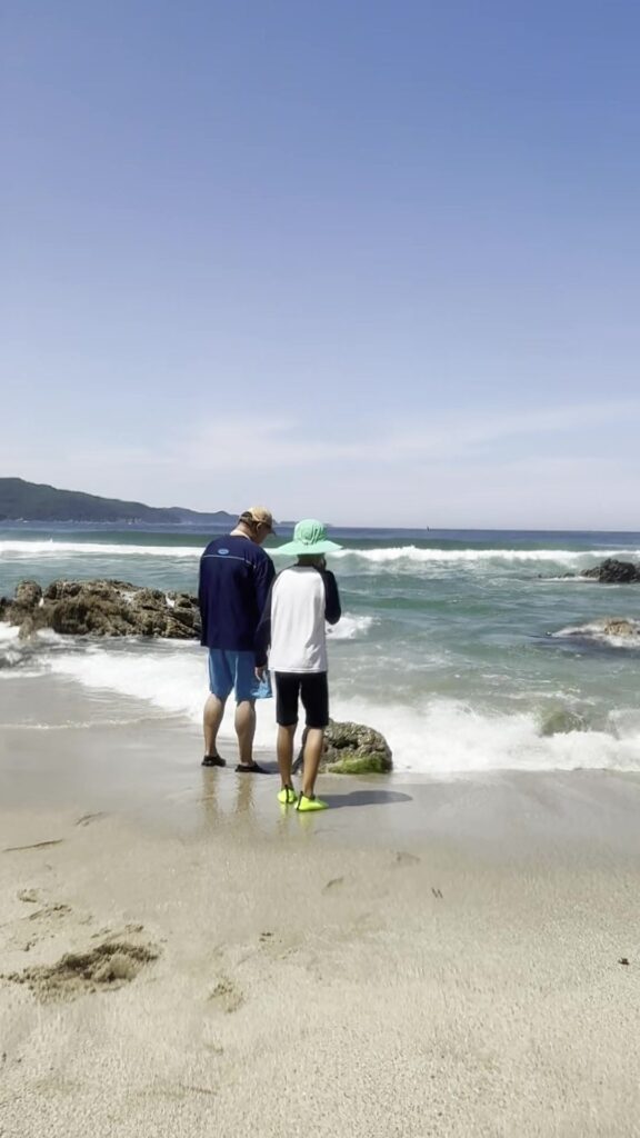 Dad and son at the shoreline of Munam Beach Samcheok watching the surf
