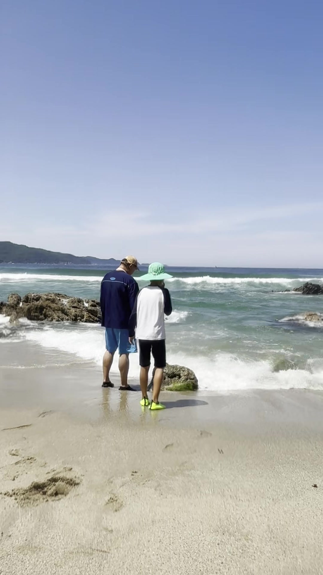Dad and son at the shoreline of Munam Beach Samcheok watching the surf