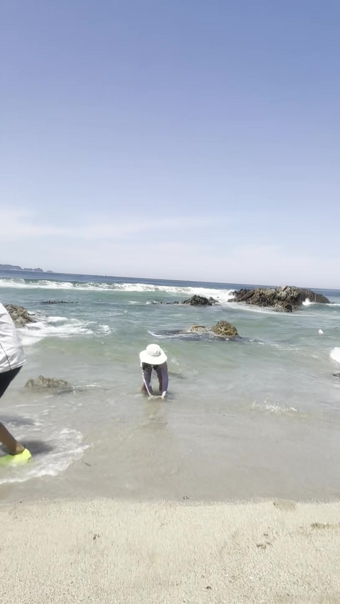 Child digging for clams in the shallow surf at Munam Beach Samcheok