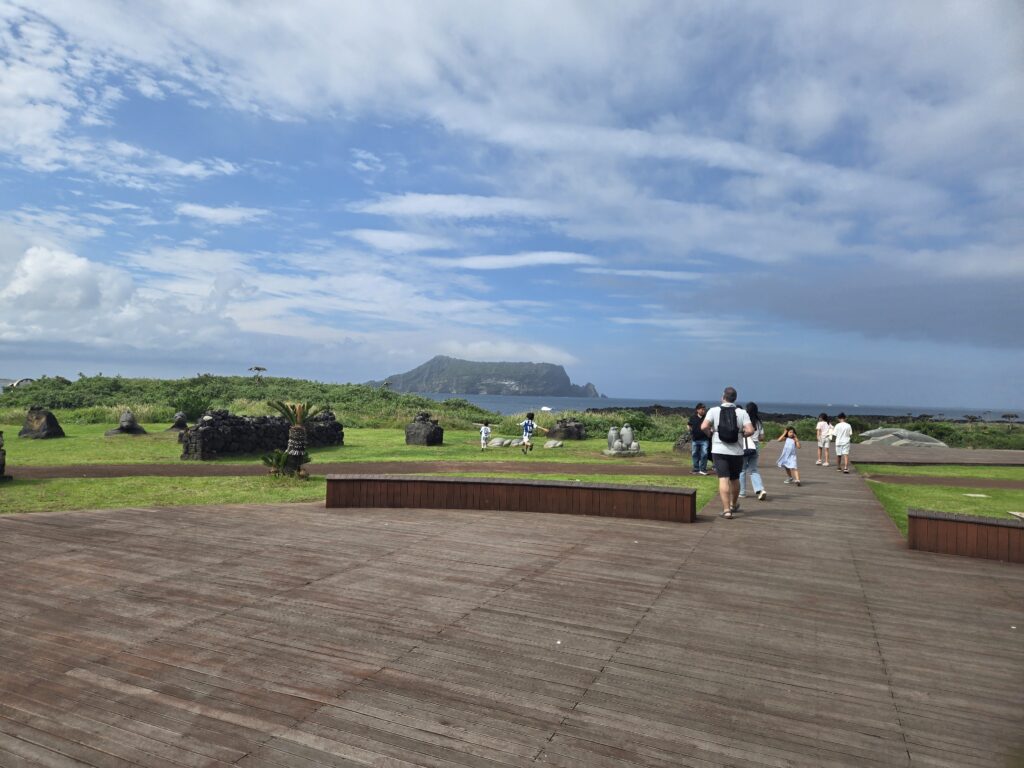 Outdoor boardwalk with Seongsan Ilchulbong behind Aqua Planet Jeju