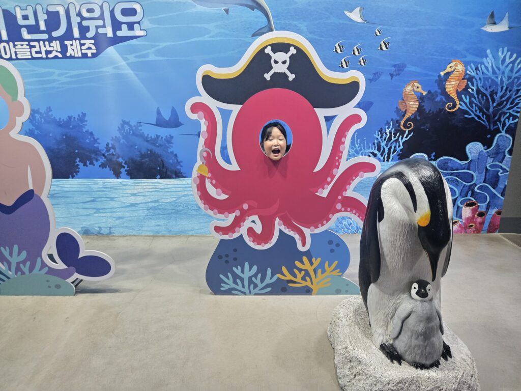 Child posing in an octopus photo cutout at Aqua Planet Jeju