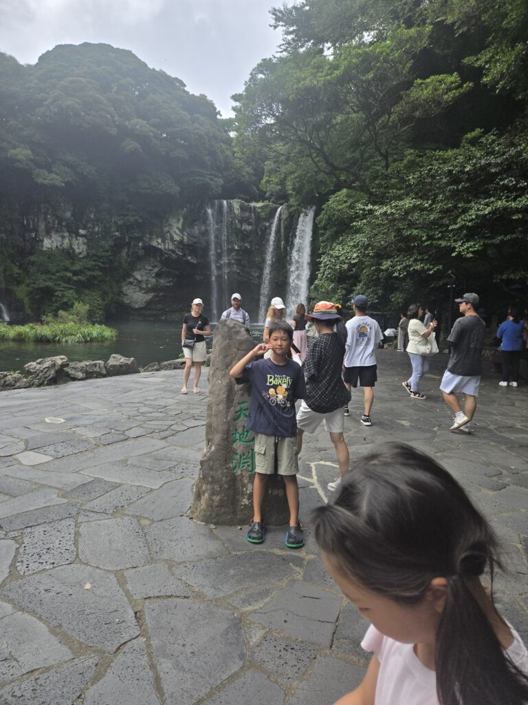Cheonjiyeon Waterfall with visitors and the name stone marker