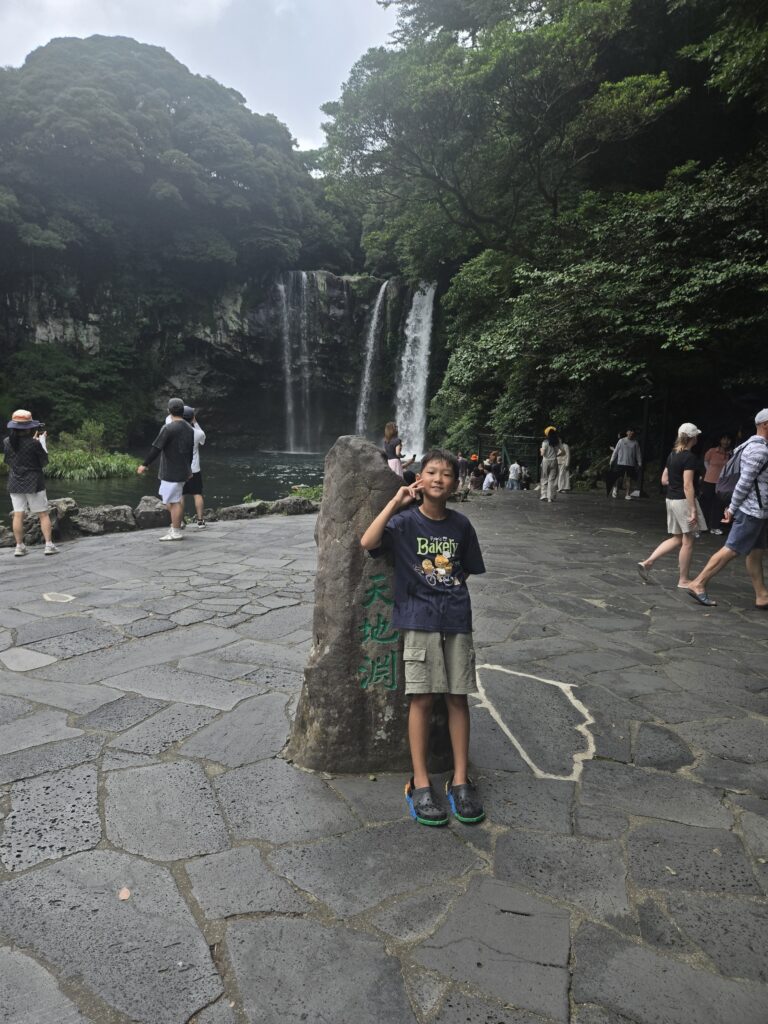 Child sitting on the Cheonjiyeon Waterfall name stone