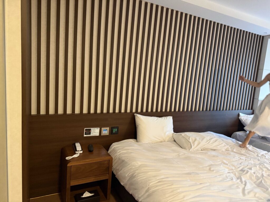Hotel Aircity Jeju twin beds against a wood feature wall
