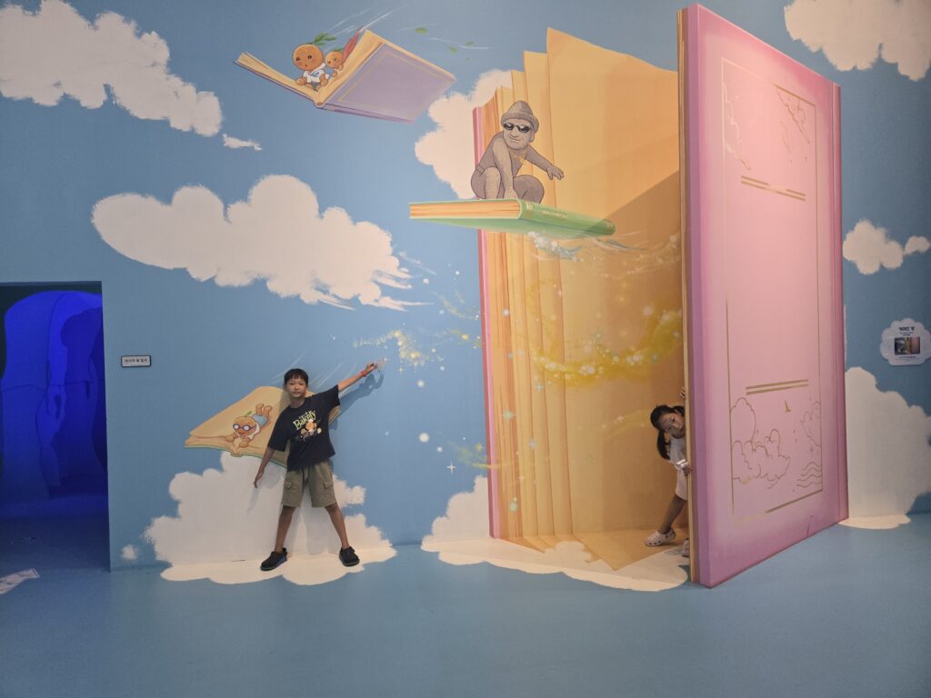 Older child posing with a giant flying book illusion at the Jeju trick art museum
