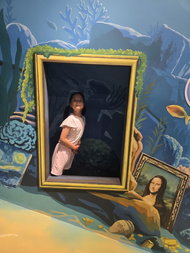 Child lying inside an underwater picture-frame illusion at the Jeju trick art museum