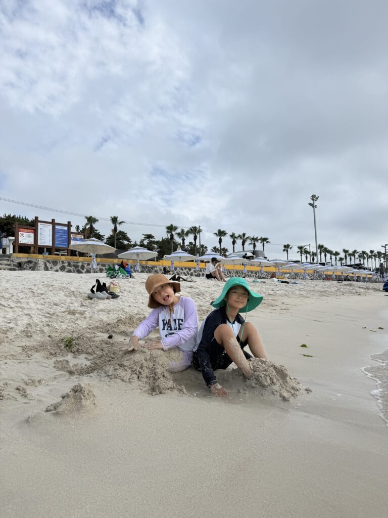 Kids playing on the sand by the palm promenade at Segial Beach Jeju