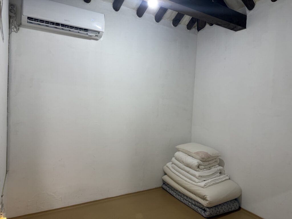 Bedroom with wooden beams and floor bedding at the hanok stay
