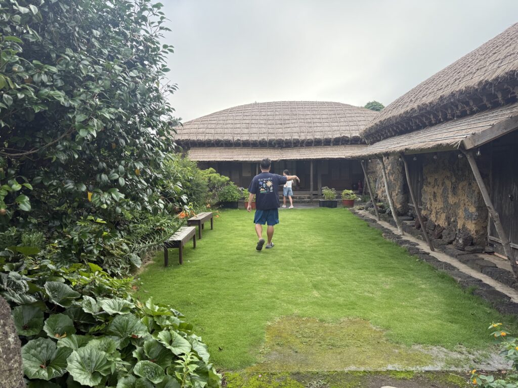 Crossing the grassy courtyard toward the thatched hanok