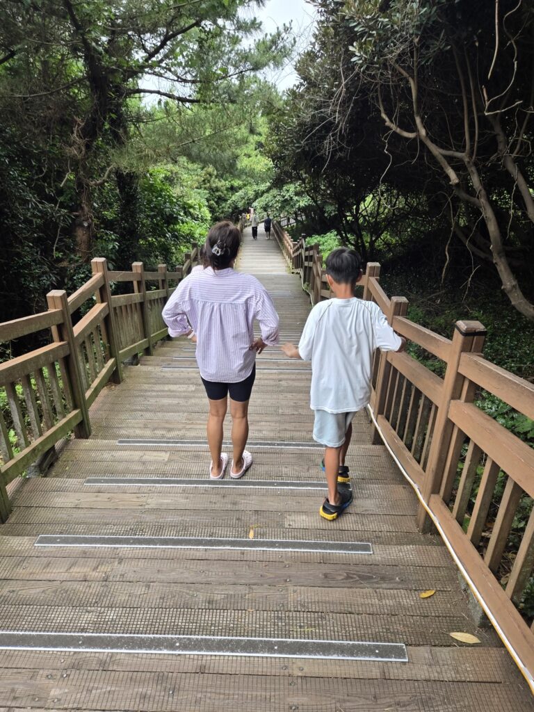 Kids on the boardwalk path at Seongsan Ilchulbong with the coast behind