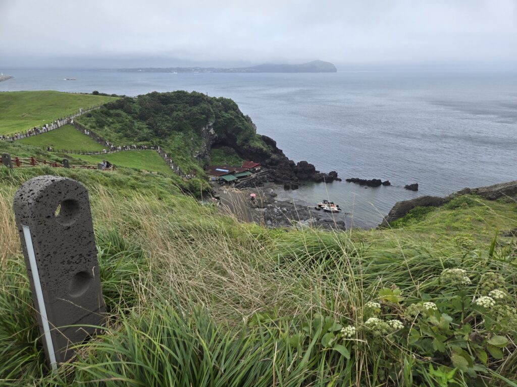 Coastal cliff and haenyeo house below Seongsan Ilchulbong