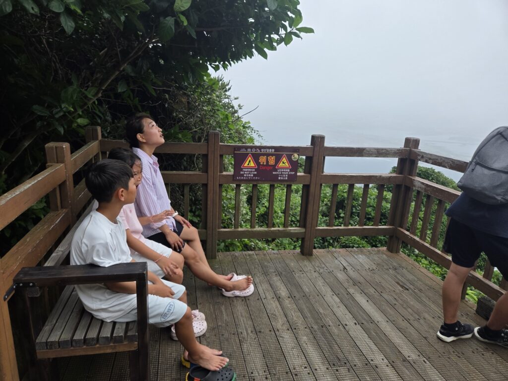 Kids resting on a bench partway up Seongsan Ilchulbong