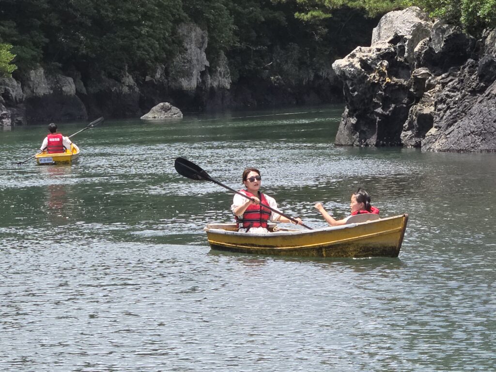 Paddling a yellow boat past volcanic cliffs at Soesokkak with kids