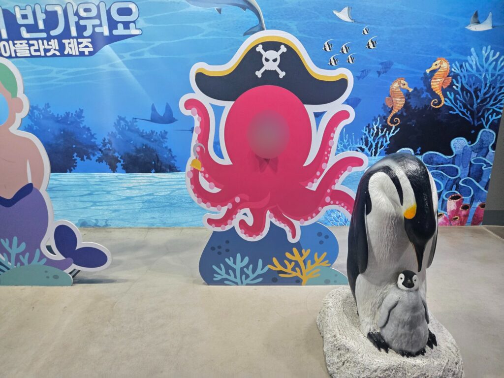 Child posing in an octopus photo cutout at Aqua Planet Jeju