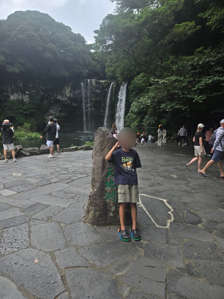 Child sitting on the Cheonjiyeon Waterfall name stone
