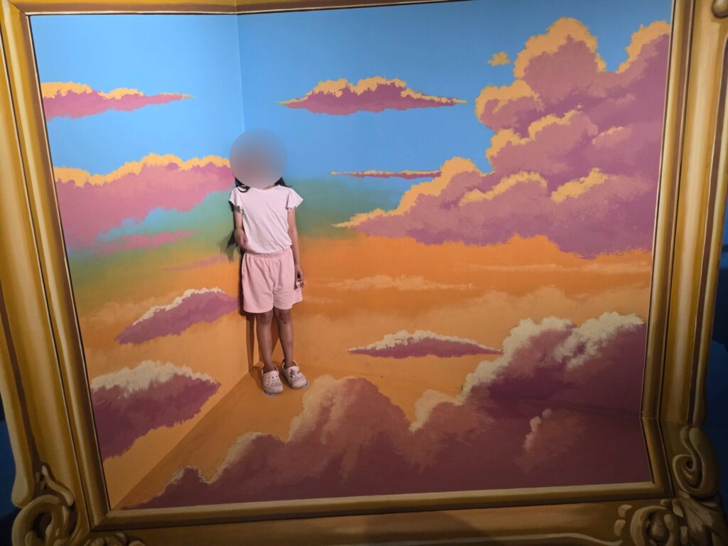 Child standing in a cloud picture-frame room at the Jeju trick art museum