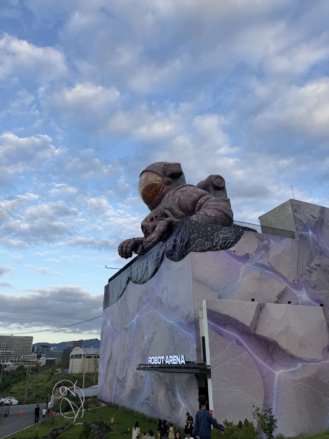 Giant astronaut figure leaning over the roof of the Robot Arena building