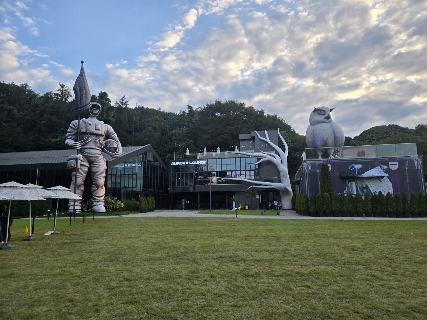 Tall astronaut statue and inflatable figures in front of glass buildings at Galaxy Robot Park