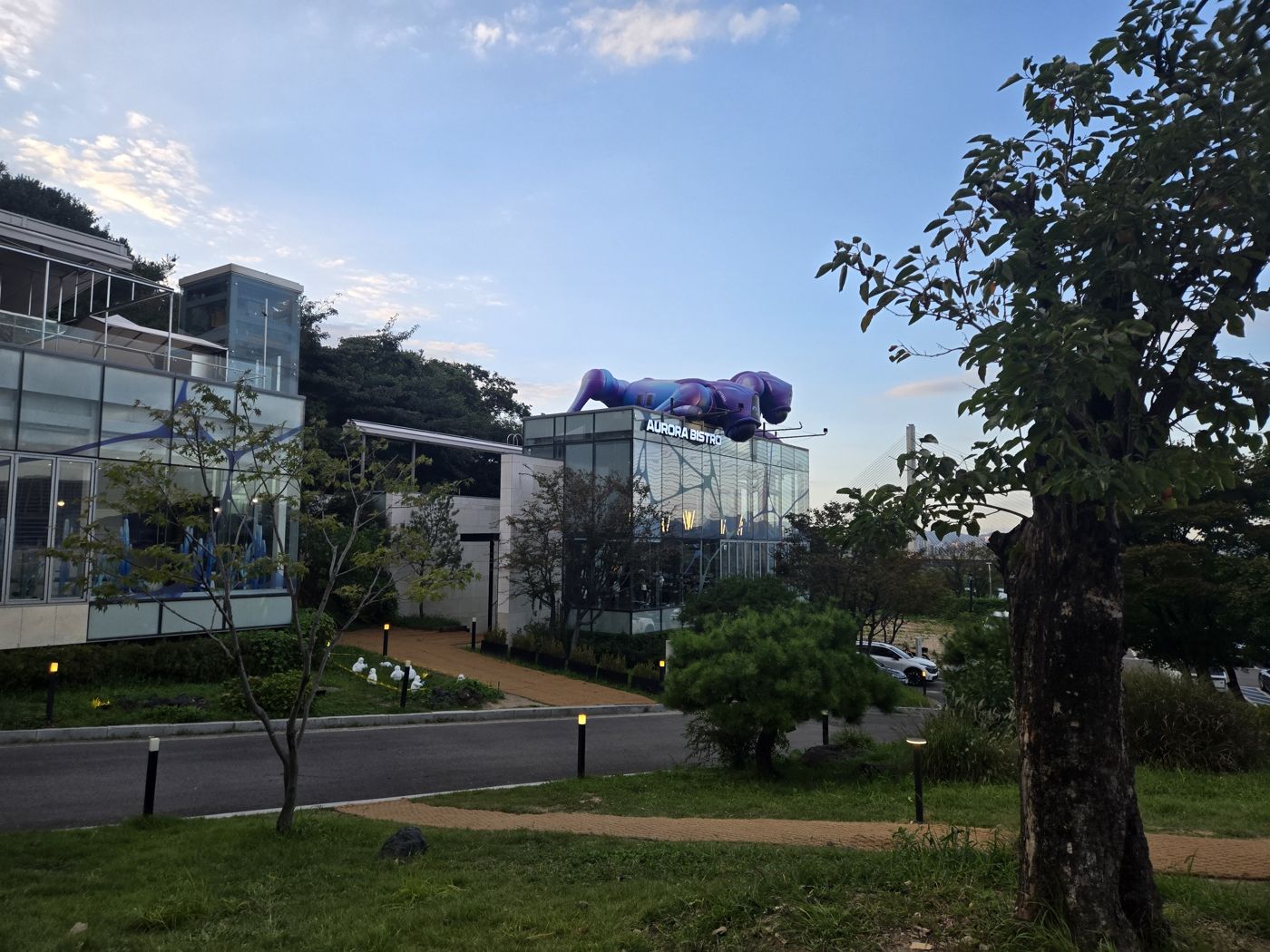 Purple inflatable robot dog lying on the roof of the Aurora Bistro glass building