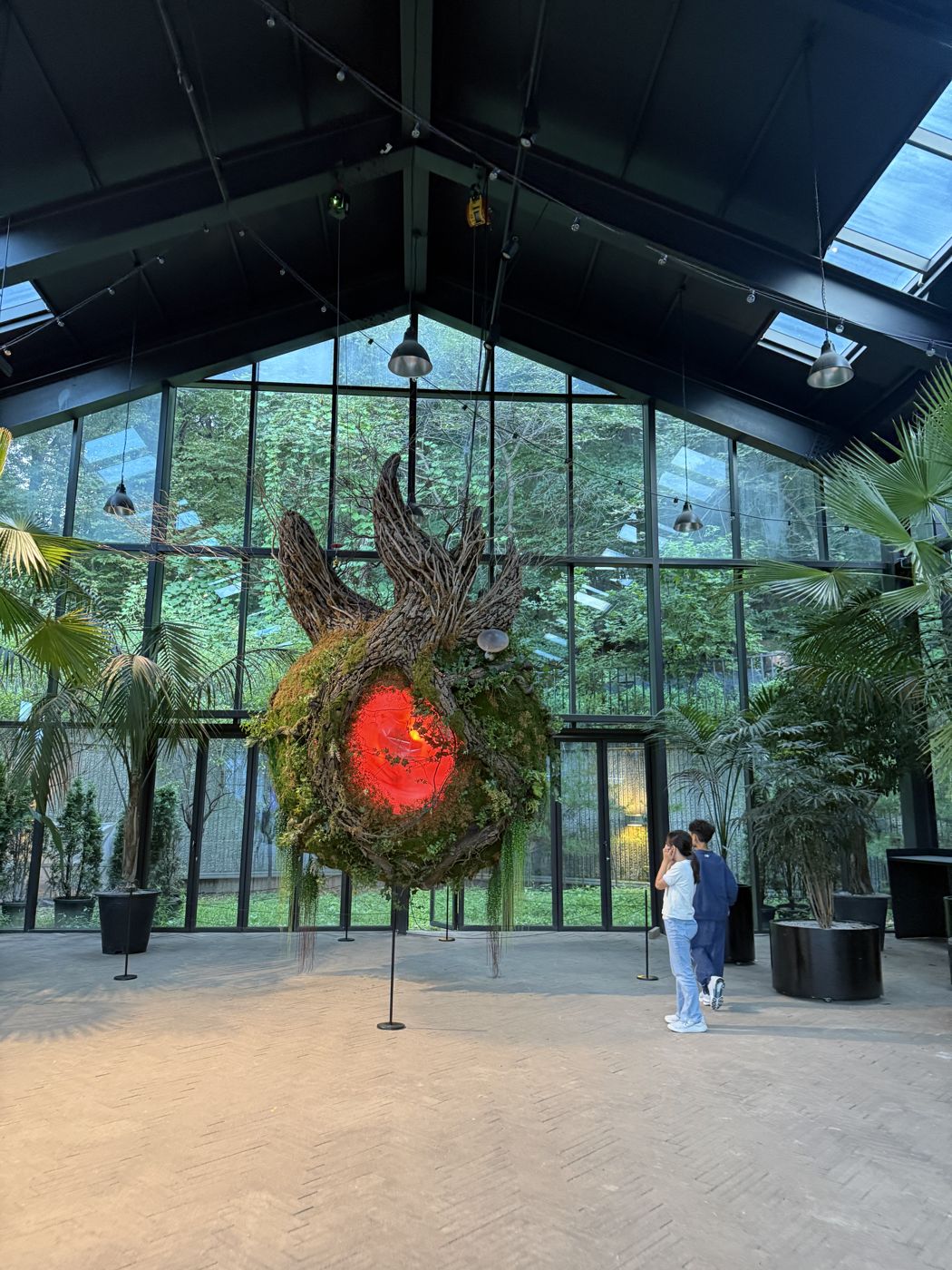 Large round installation of greenery with a glowing red center inside the greenhouse
