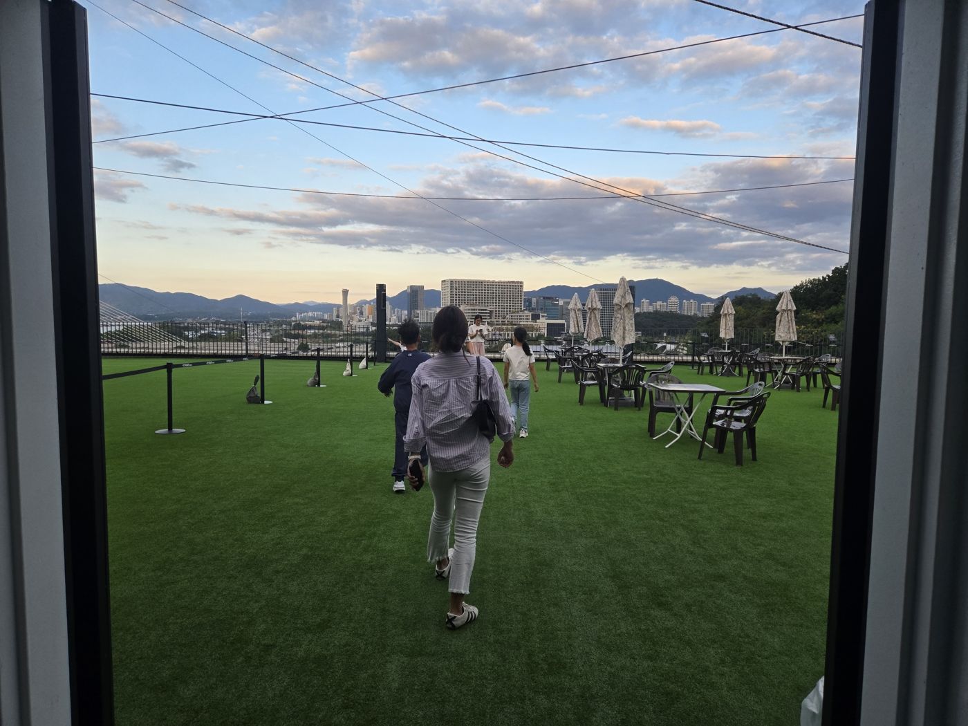 Family walking onto the artificial grass rooftop with city and mountain views