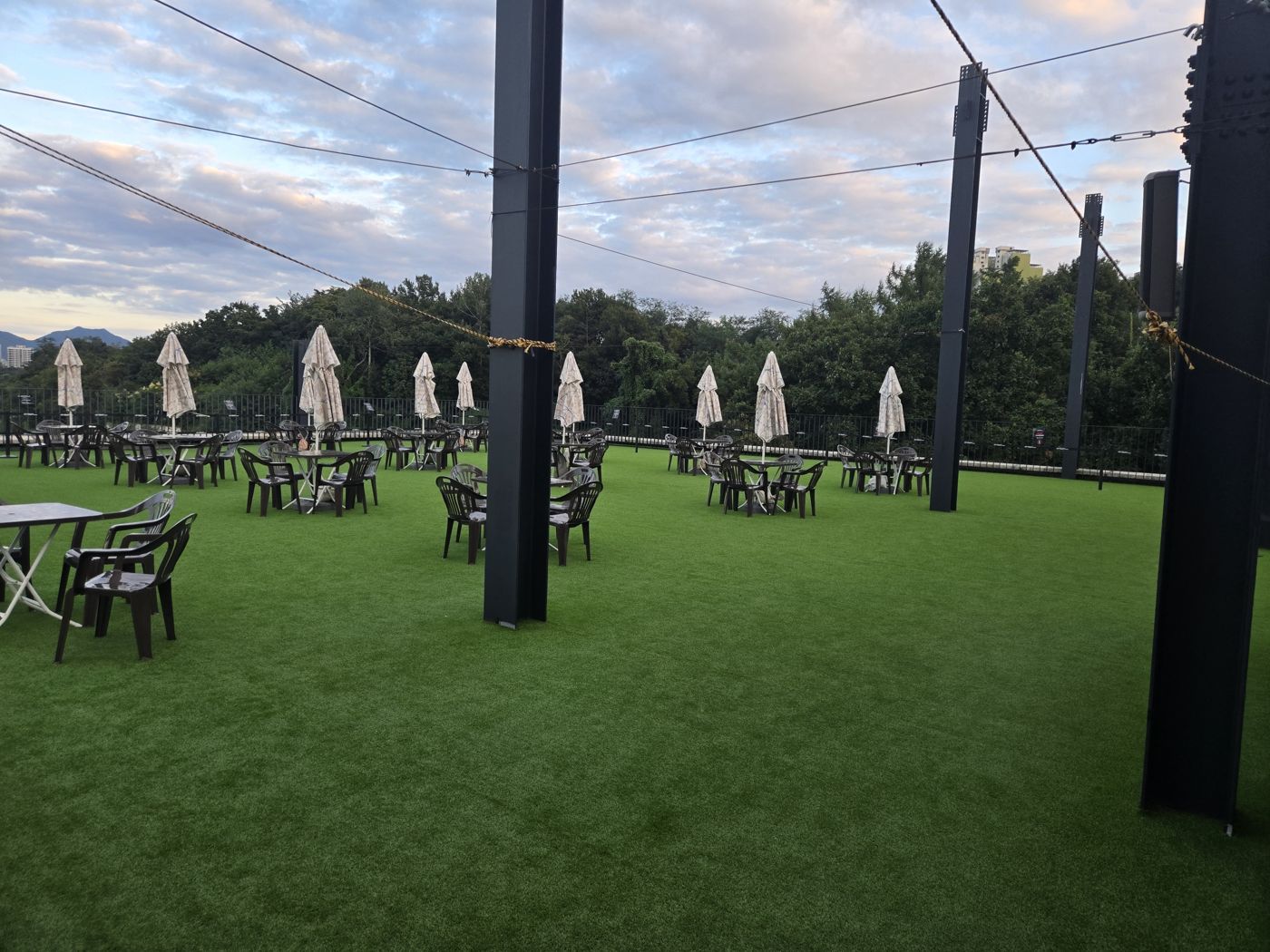 Rows of tables and chairs with folded parasols on the Robot Arena rooftop lawn