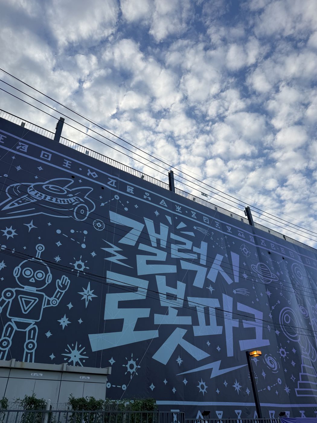 Galaxy Robot Park lettering and robot drawings on a dark wall under a cloudy sky