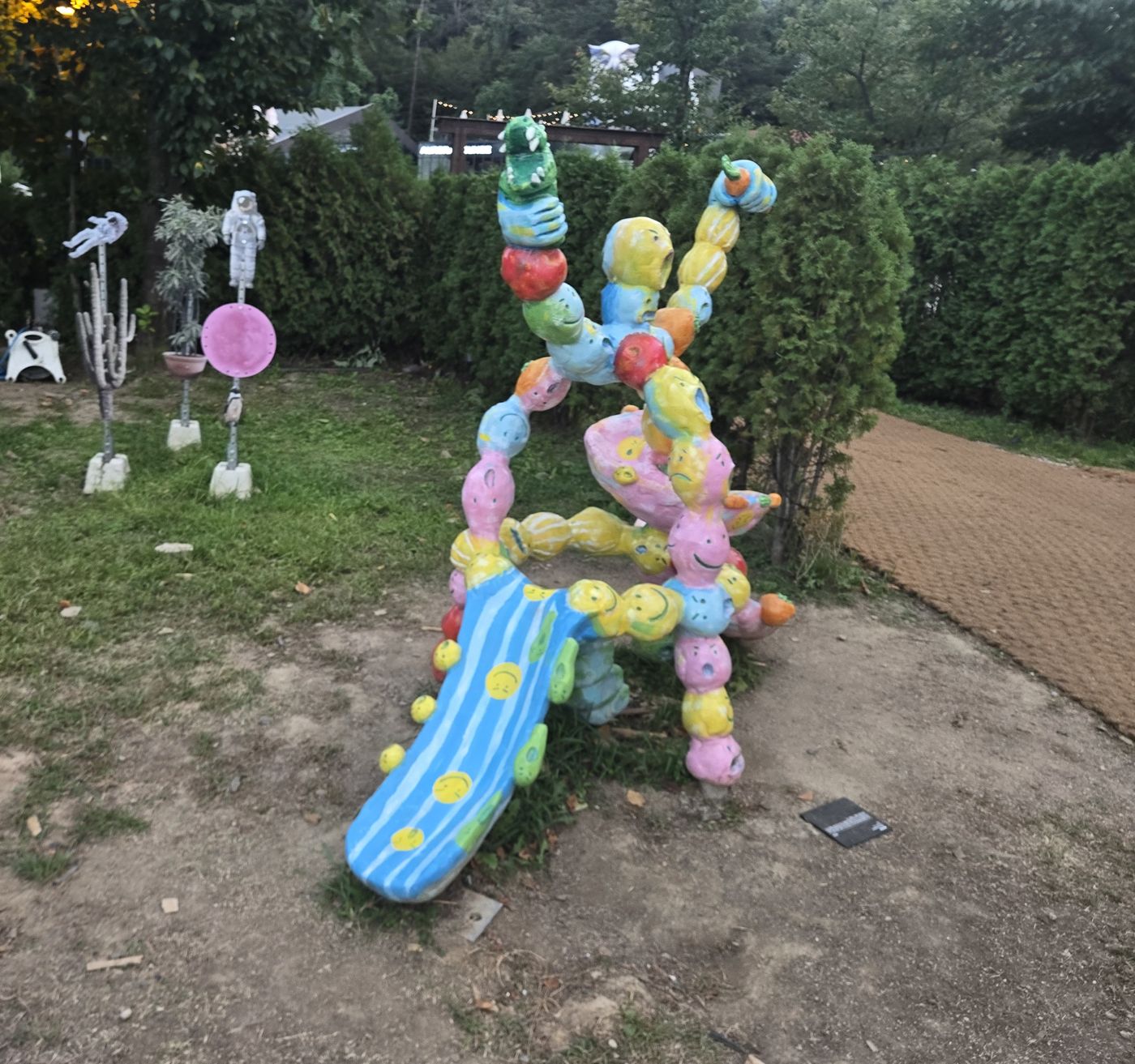 Colorful slide sculpture and space-themed figures on poles in the garden