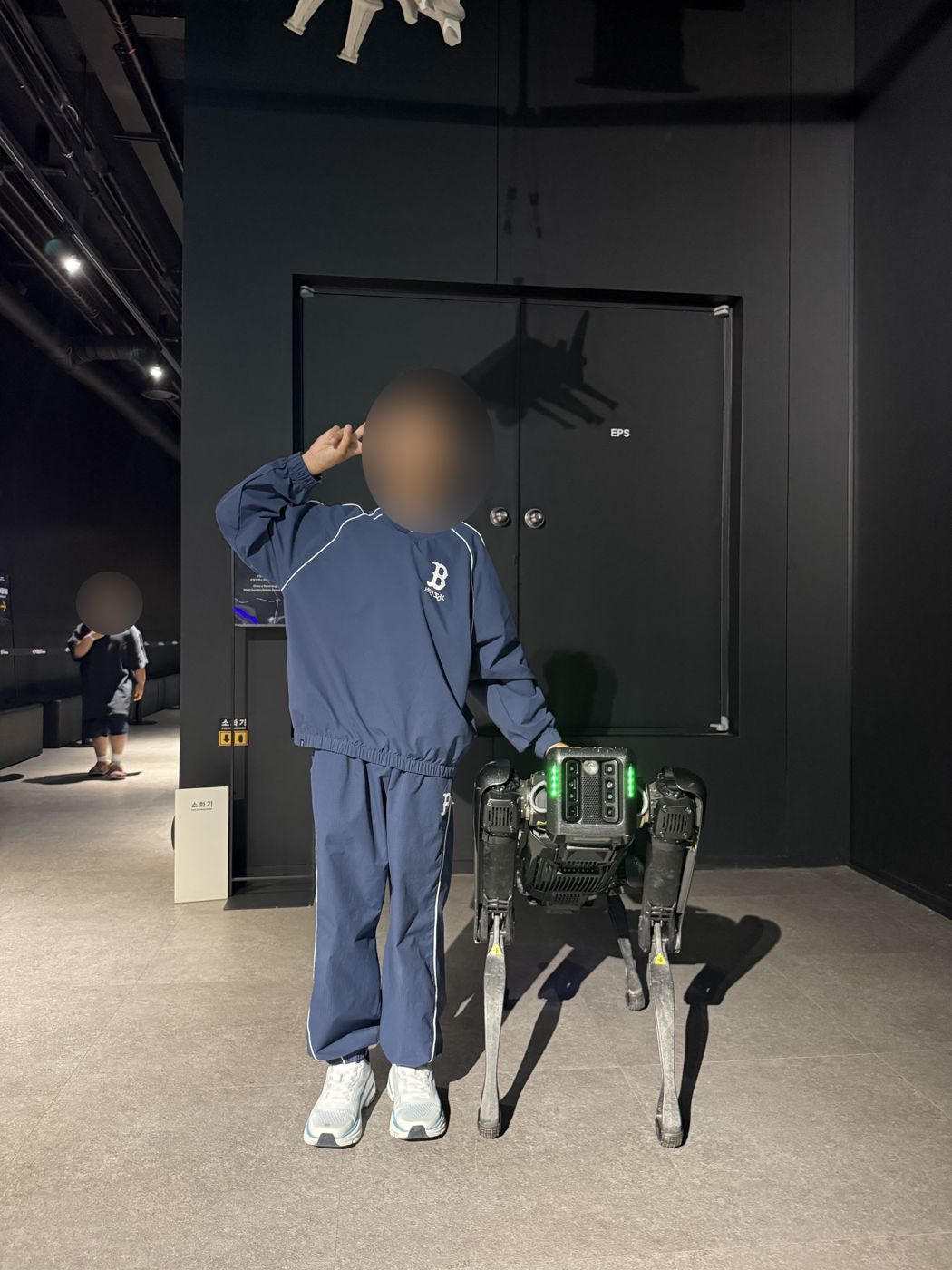 Boy standing next to a robot dog inside the Robot Arena lobby