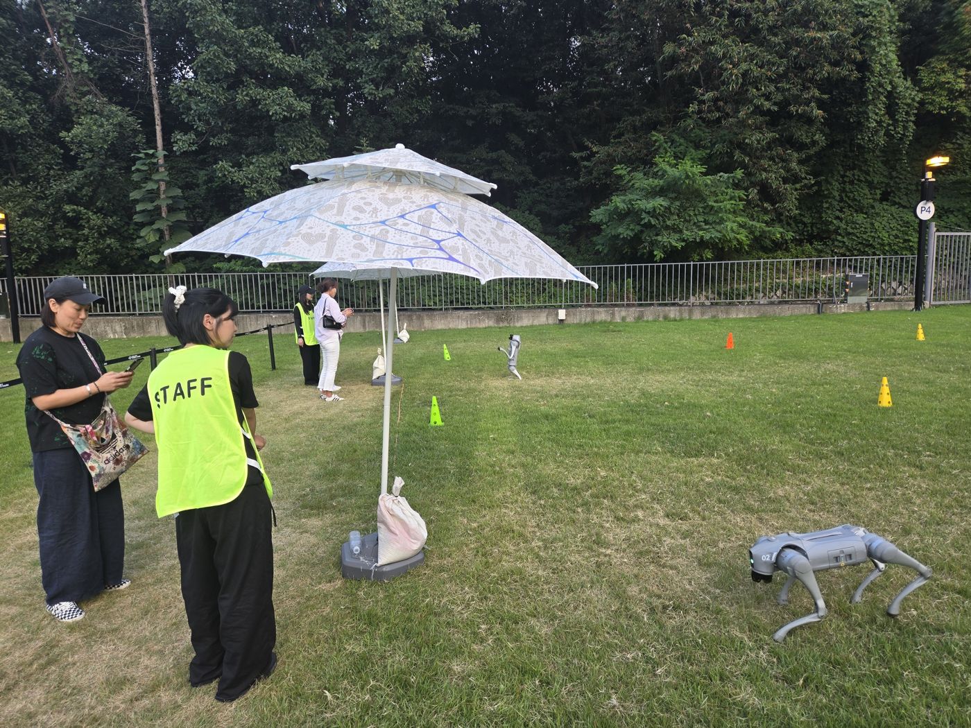 Staff member in a yellow vest next to a robot dog on the lawn course