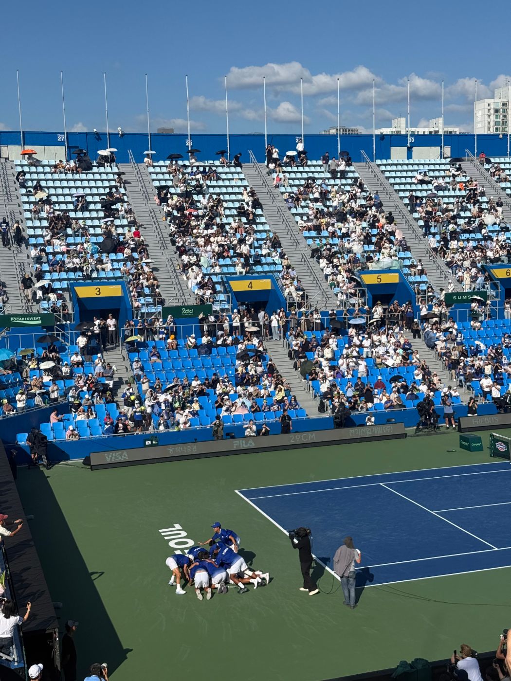Korean players piled on top of each other on the court after winning the tie