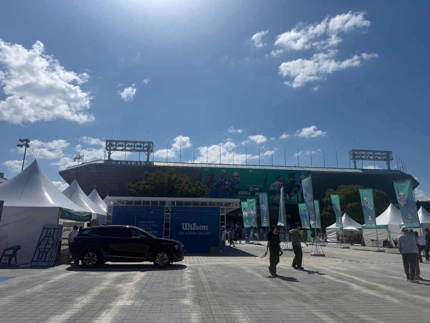 Olympic Tennis Court exterior with a large Davis Cup Korea vs India banner, white tents and a Wilson booth