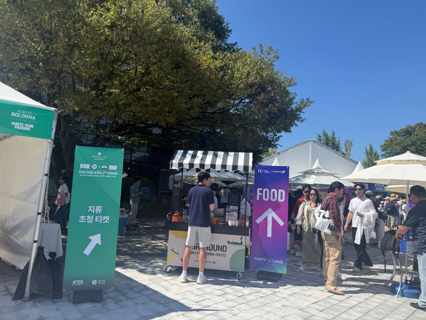 A purple Food arrow sign, a coffee cart and a sign for paper invitation tickets