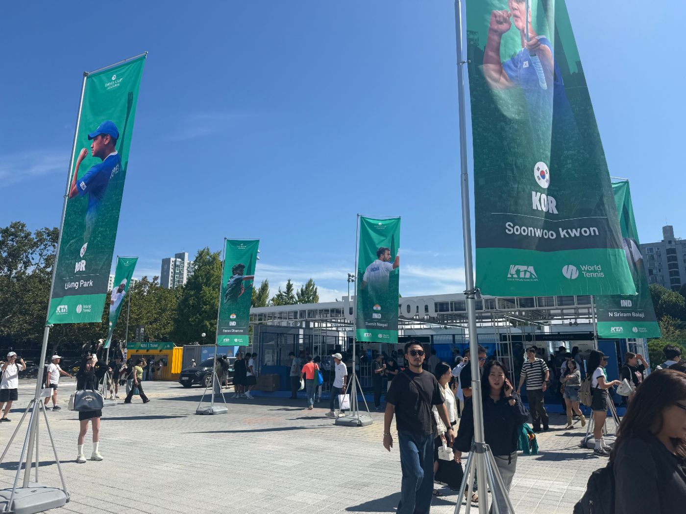 Plaza outside Olympic Tennis Court with player banners for Korea and India and the Wilson booth